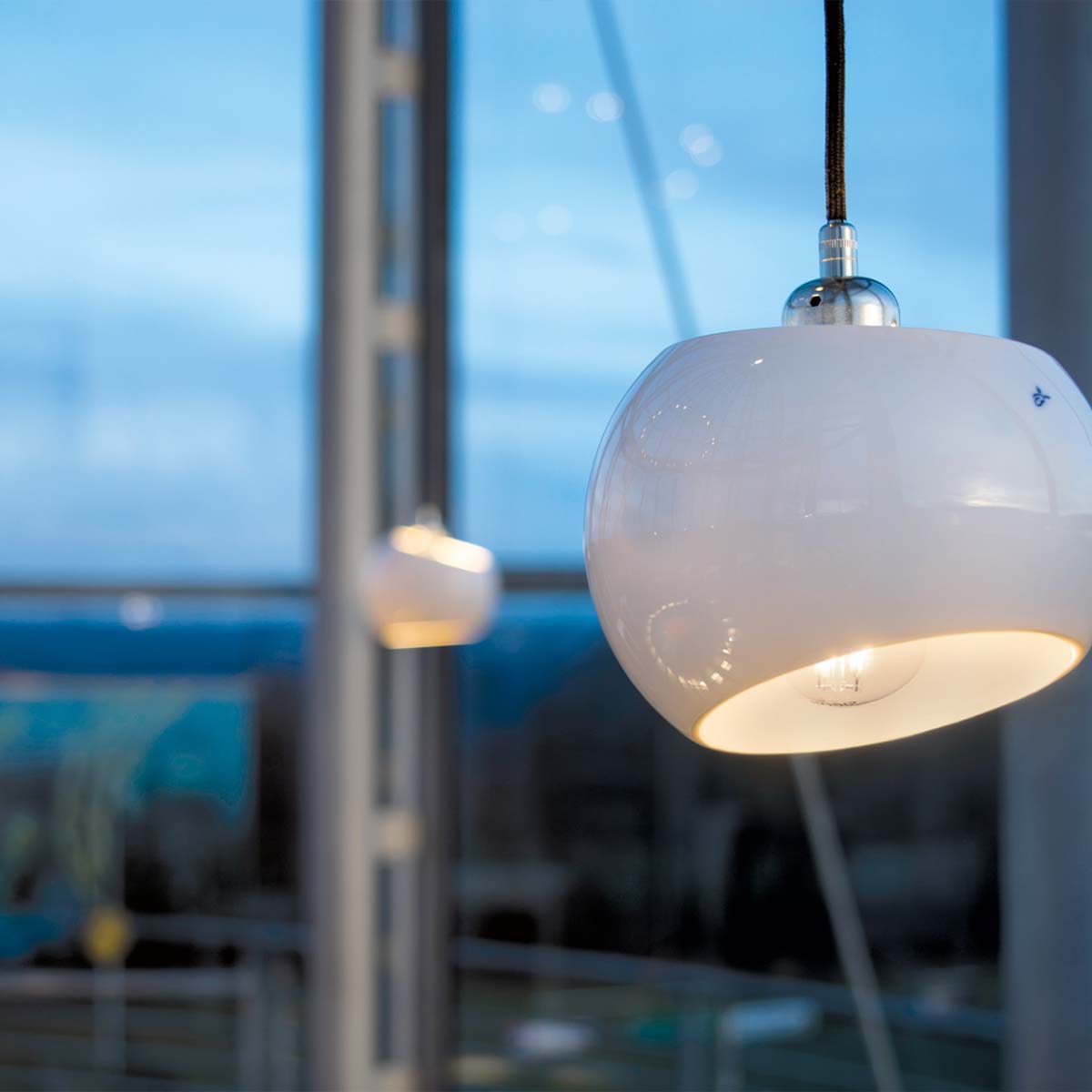 White Moons 1 Pendelleuchte, Ø: 16,5 cm, Alu poliert Zwei moderne weiße Pendelleuchten mit schrägem Lampenschirm, hängend an einem schwarzen Kabel