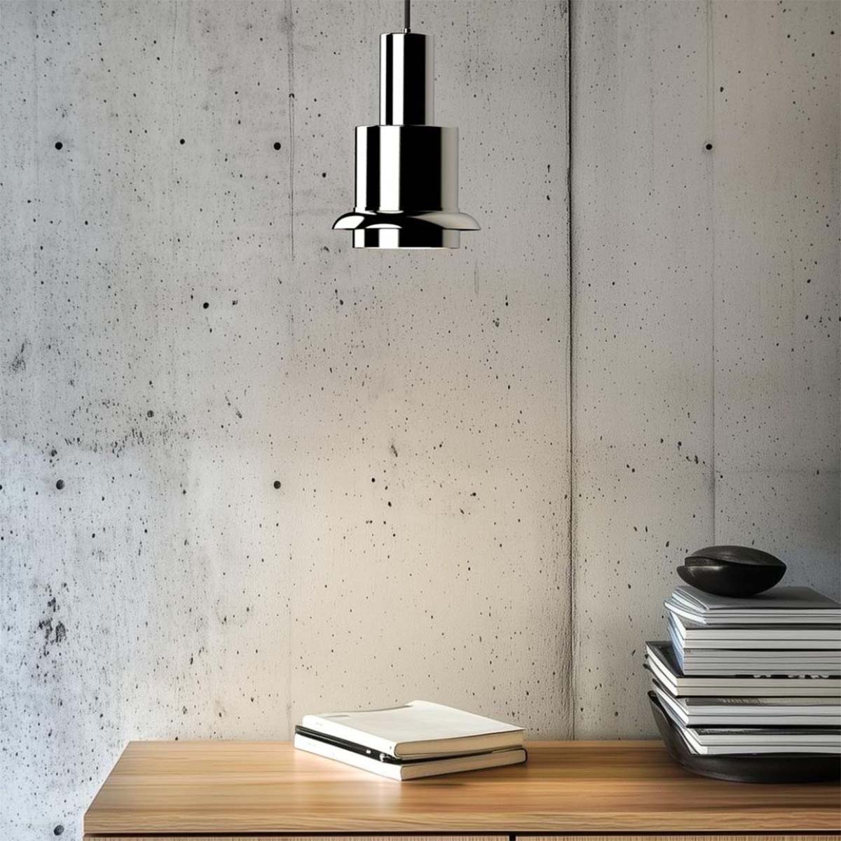 DCW Editions Chaumont 150 in modernem Arbeitsbereich – verchromte Pendelleuchte über Holztisch mit Büchern, minimalistisches Design mit industriellem Betonhintergrund