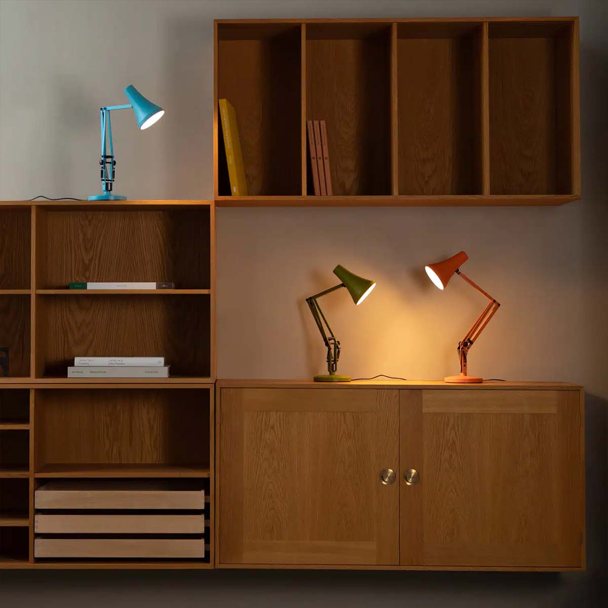 Moderne Tischleuchten in Blau, Grün und Orange auf Holzmöbeln mit warmem Licht, ideal für gemütliche Wohnräume und zeitloses Design Moderne Tischleuchten in Blau, Grün und Orange auf Holzmöbeln mit warmem Licht, ideal für gemütliche Wohnräume und zeitloses Design