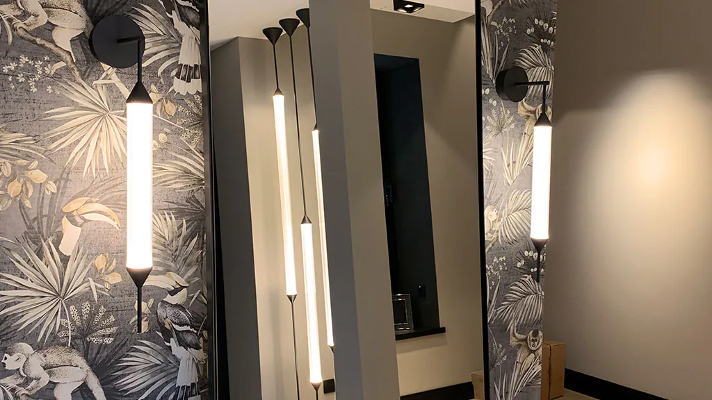 Zwei Wandleuchten von Giopatto & Coombes in Glas und schwarz links und rechts neben einem Spiegel