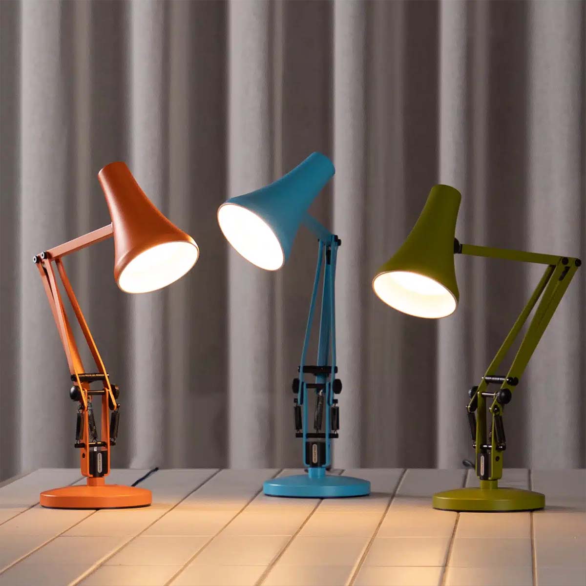 Moderne Tischlampen in Orange, Blau und Grün mit warmem Licht auf Tischfläche, stilvolle Designleuchten für modernes Interior