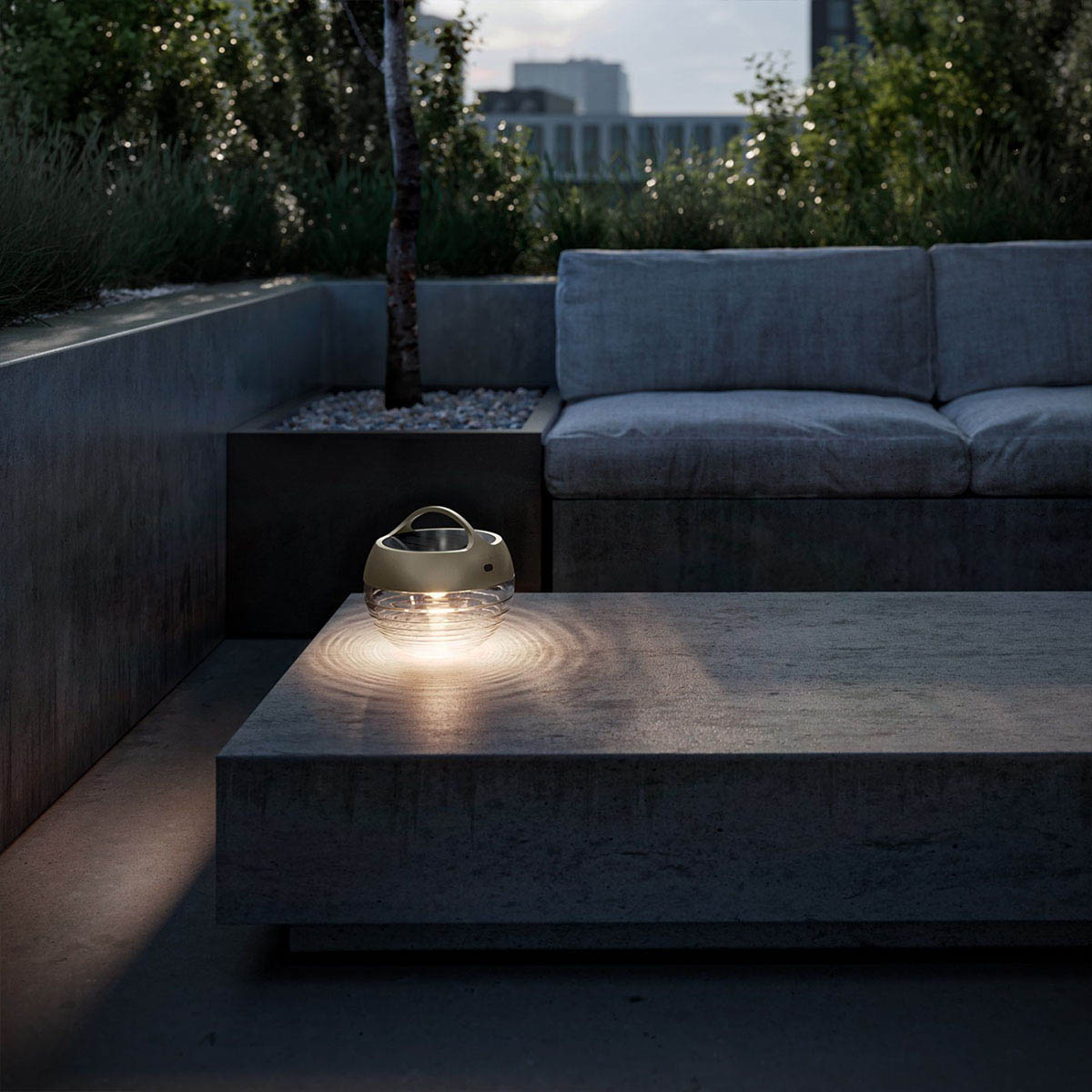 Runde mobile Akku Lampe für außen aus Glas und Metall in der Farbe Bronze im Garten auf dem Tisch