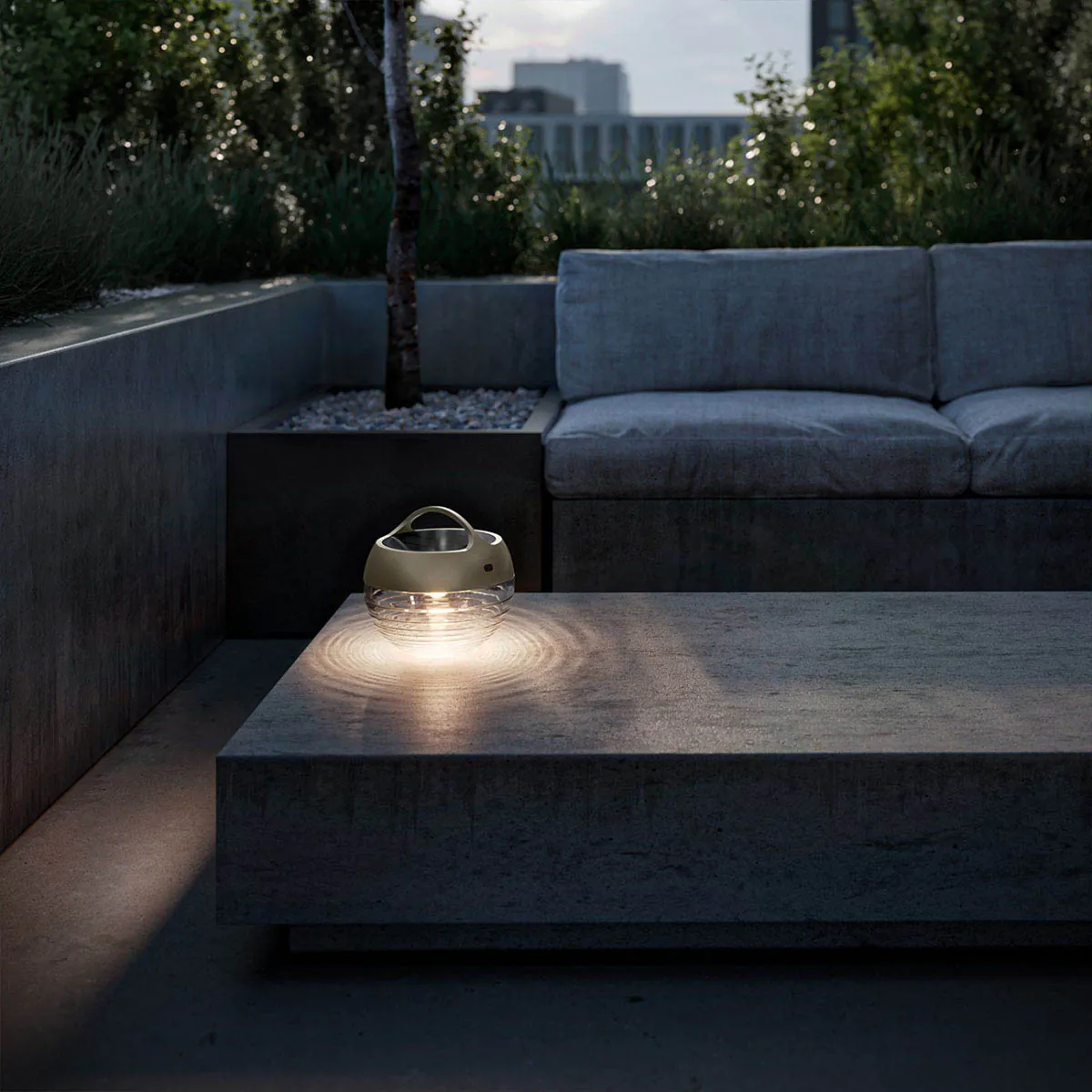 Runde mobile Akku Lampe für außen aus Glas und Metall in der Farbe Bronze im Garten auf dem Tisch