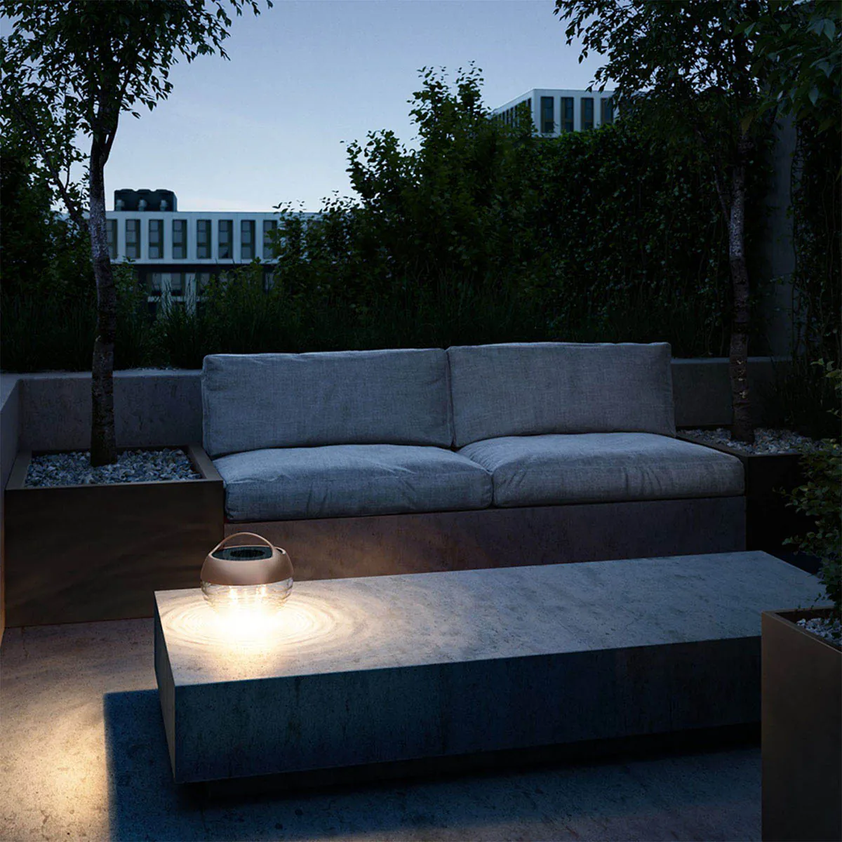 Kleine runde mobile Akku Lampe für außen aus Glas und Metall in der Farbe Bronze im Garten auf dem Tisch