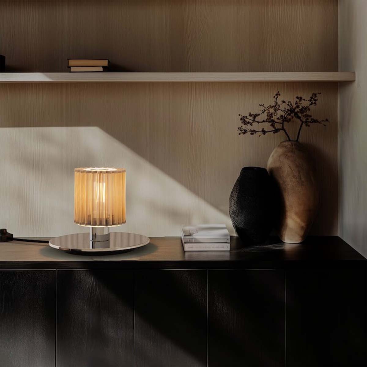 DCW Editions In The Sun Table 220 auf Sideboard – stilvolle Tischleuchte in Goldoptik auf dunklem Sideboard, harmonisch kombiniert mit Keramikvasen und sanftem Lichteinfall