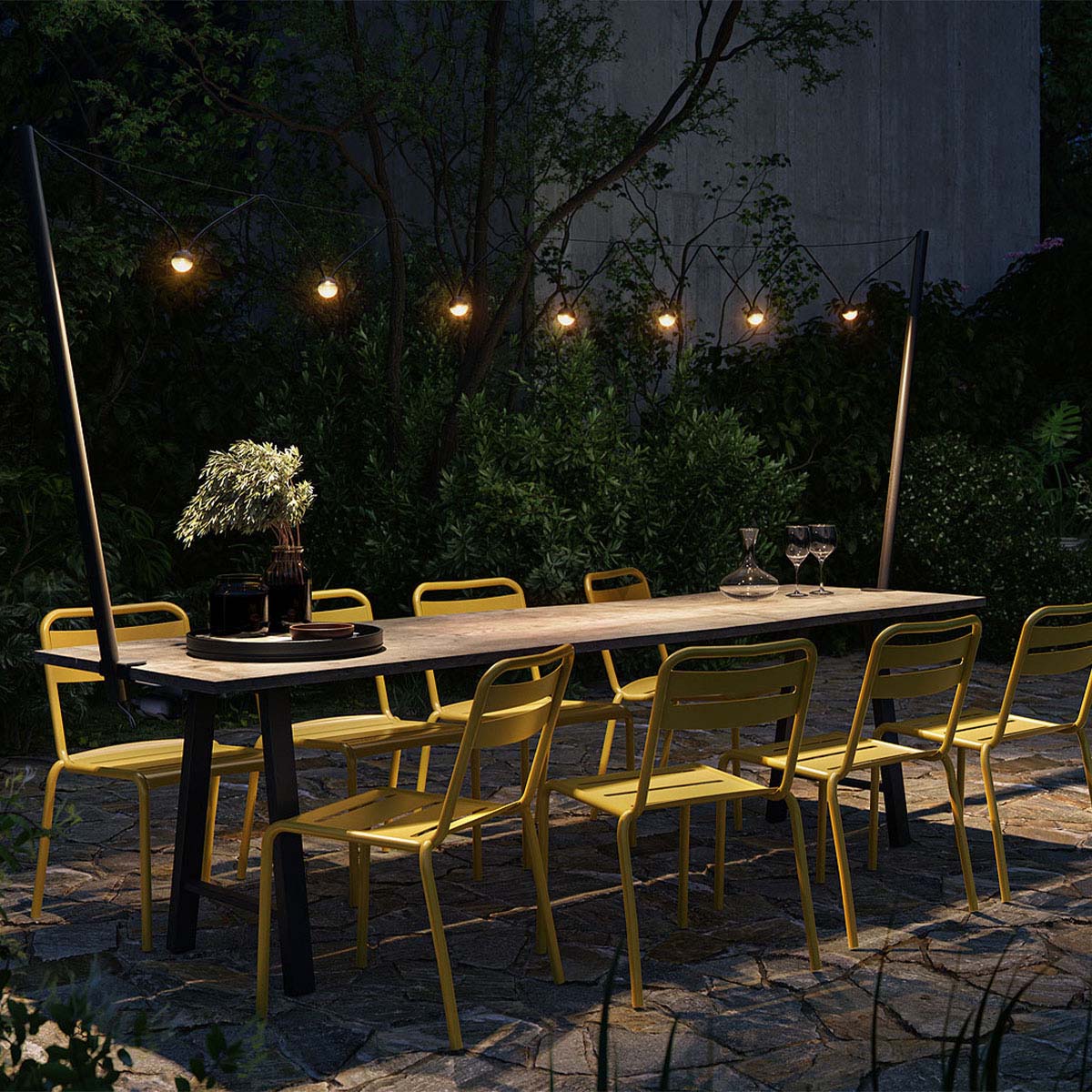 Lichterkette mit runden leuchten und schwarzem verbindungskabel leuchten über dem Esstisch im Garten am Abend