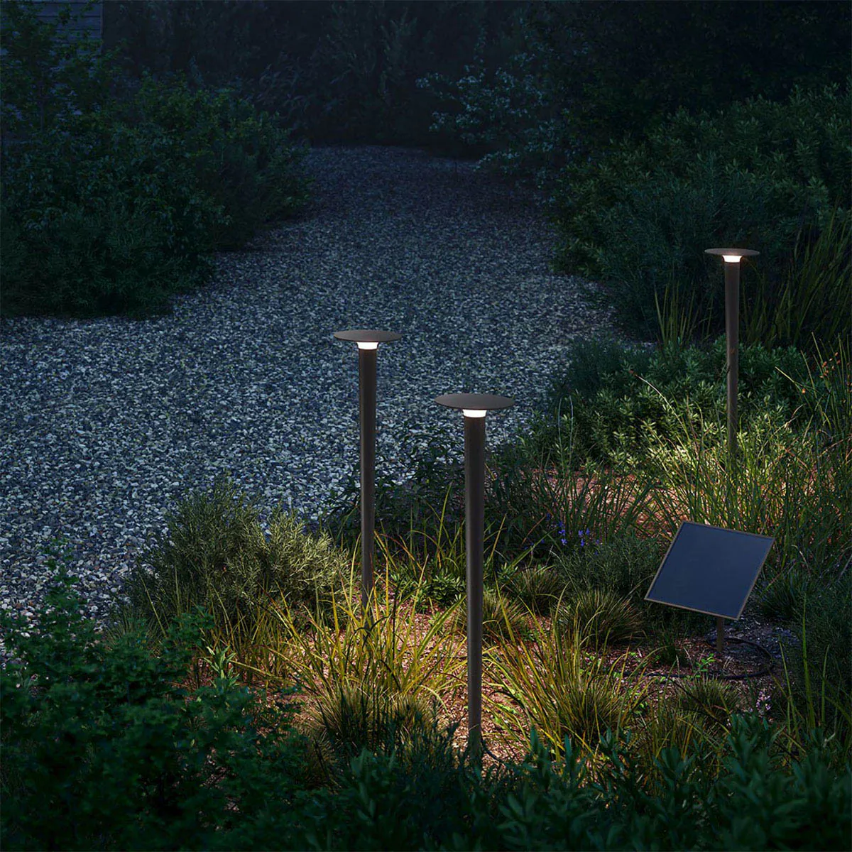 Drei längliche Erdspießleuchten schwarz mit einem Solarpanel im Garten zwischen Pflanzen