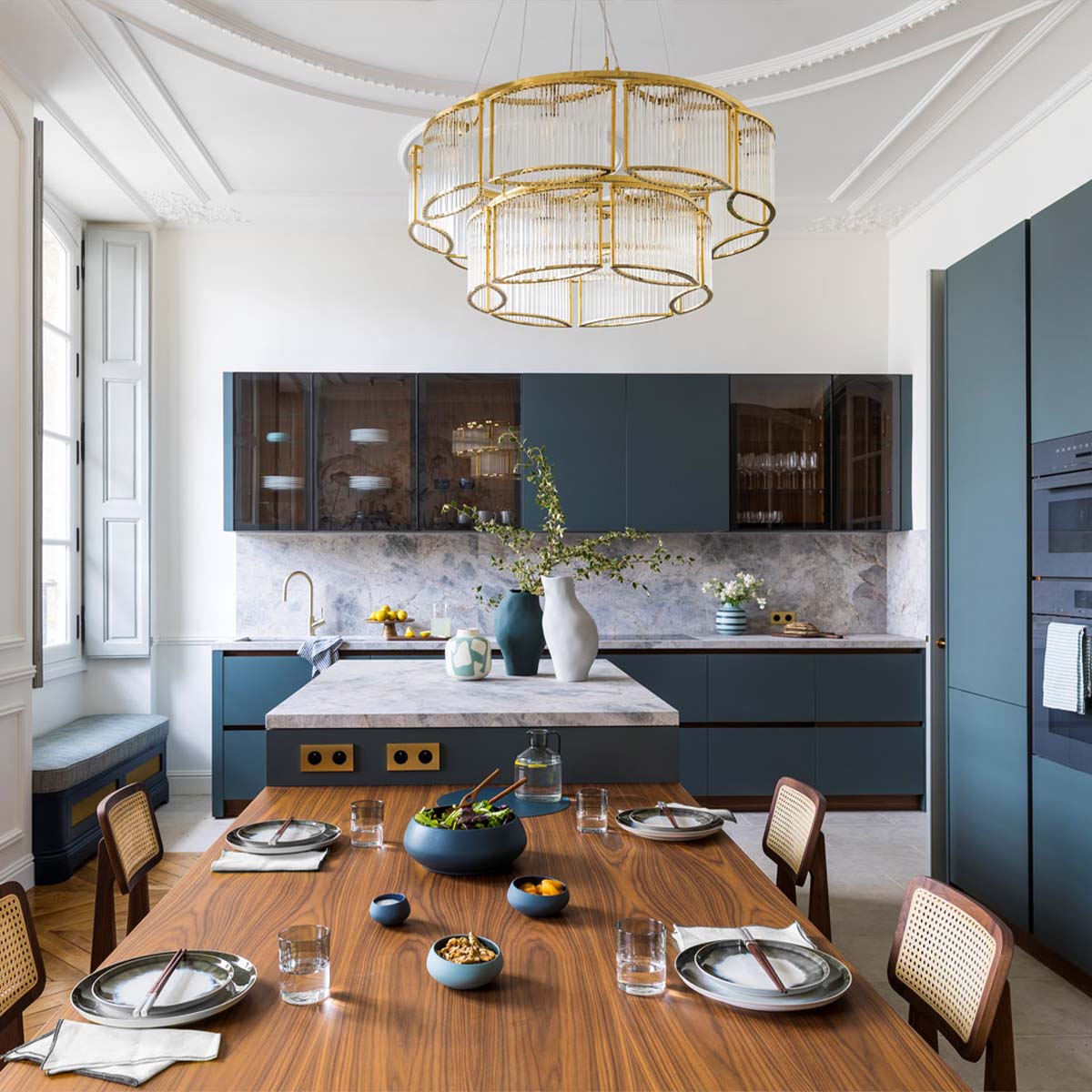 Moderner Kronleuchter mit geschwungenem Glasschirm über einen Esstisch hängend