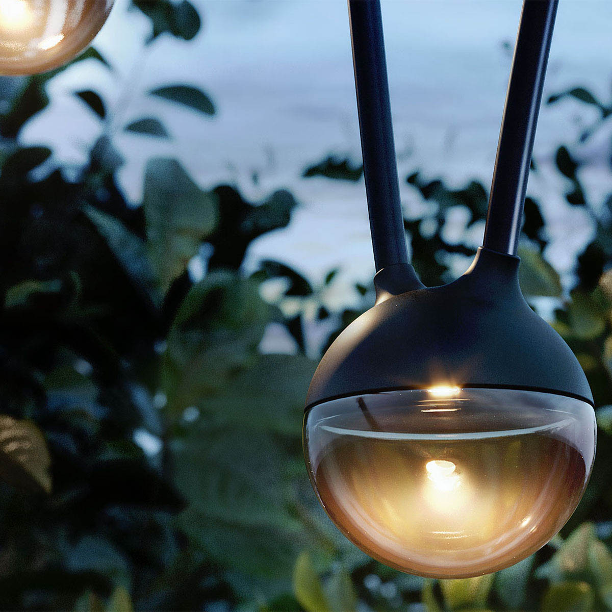 Detail von den runden Leuchten der Lichterkette im Garten am Baum hängend