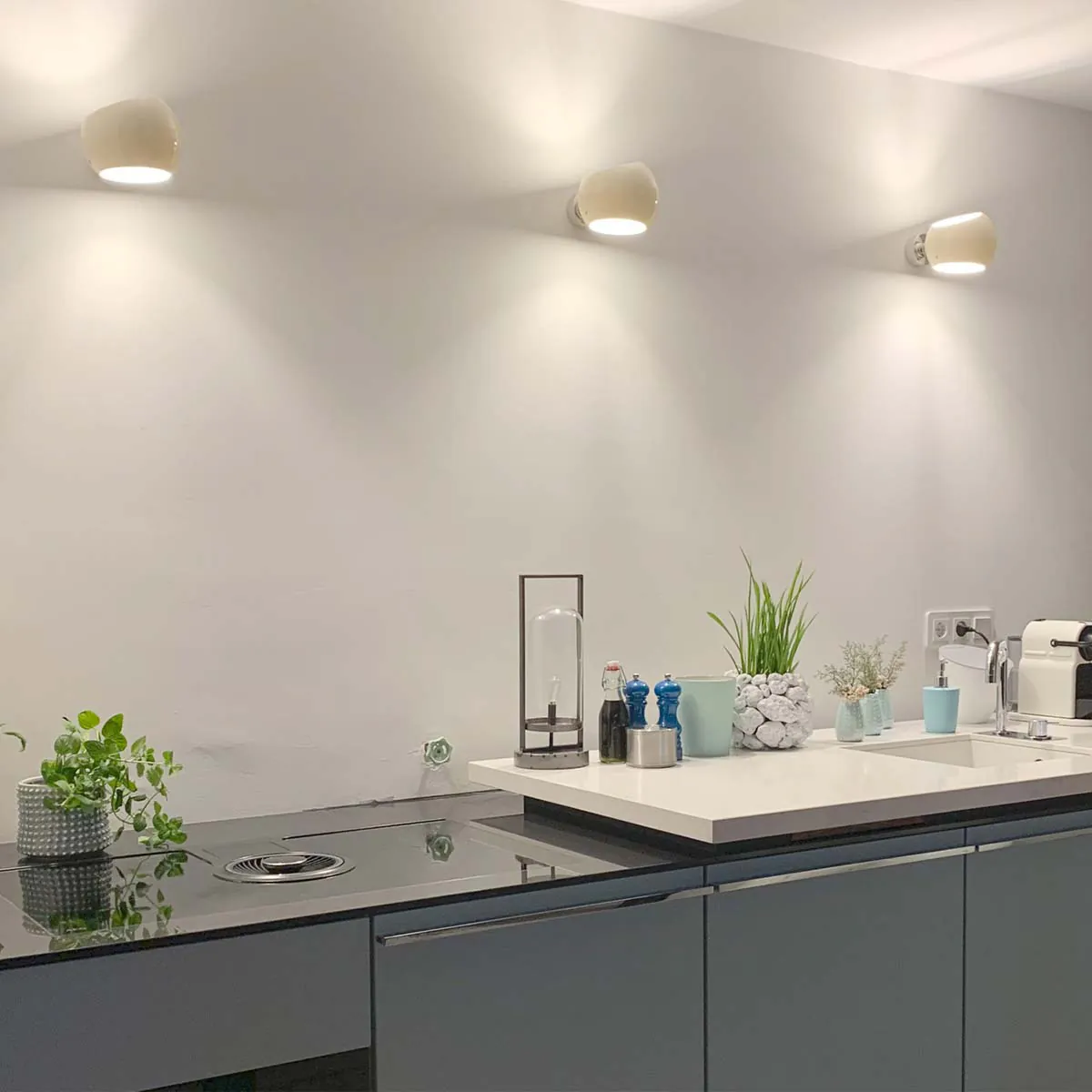 Drei moderne weiße Wandleuchten mit asymmetrischem Design in der Küche hängend