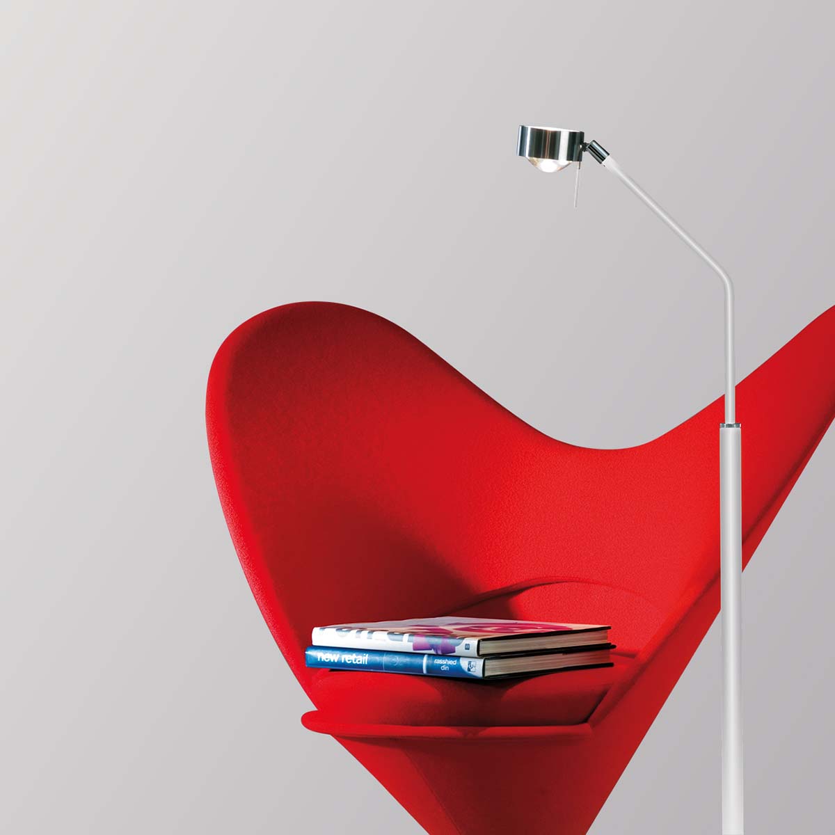 Schmale Stehleuchte in der Farbe weiß chrom neben einem Stuhl stehend