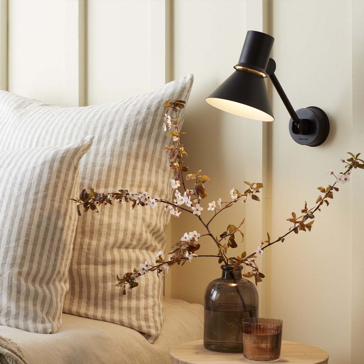 Anglepoise Type 80 W2 Wandleuchte, Ø: 14,5 cm, H: 16 cm im Wohnambiente: schwarze Design-Wandleuchte neben Bett mit warmem Licht und dekorativen Blütenzweigen im Schlafzimmer. Anglepoise Type 80 W2 Wandleuchte, Ø: 14,5 cm, H: 16 cm im Wohnambiente: schwarze Design-Wandleuchte neben Bett mit warmem Licht und dekorativen Blütenzweigen im Schlafzimmer.