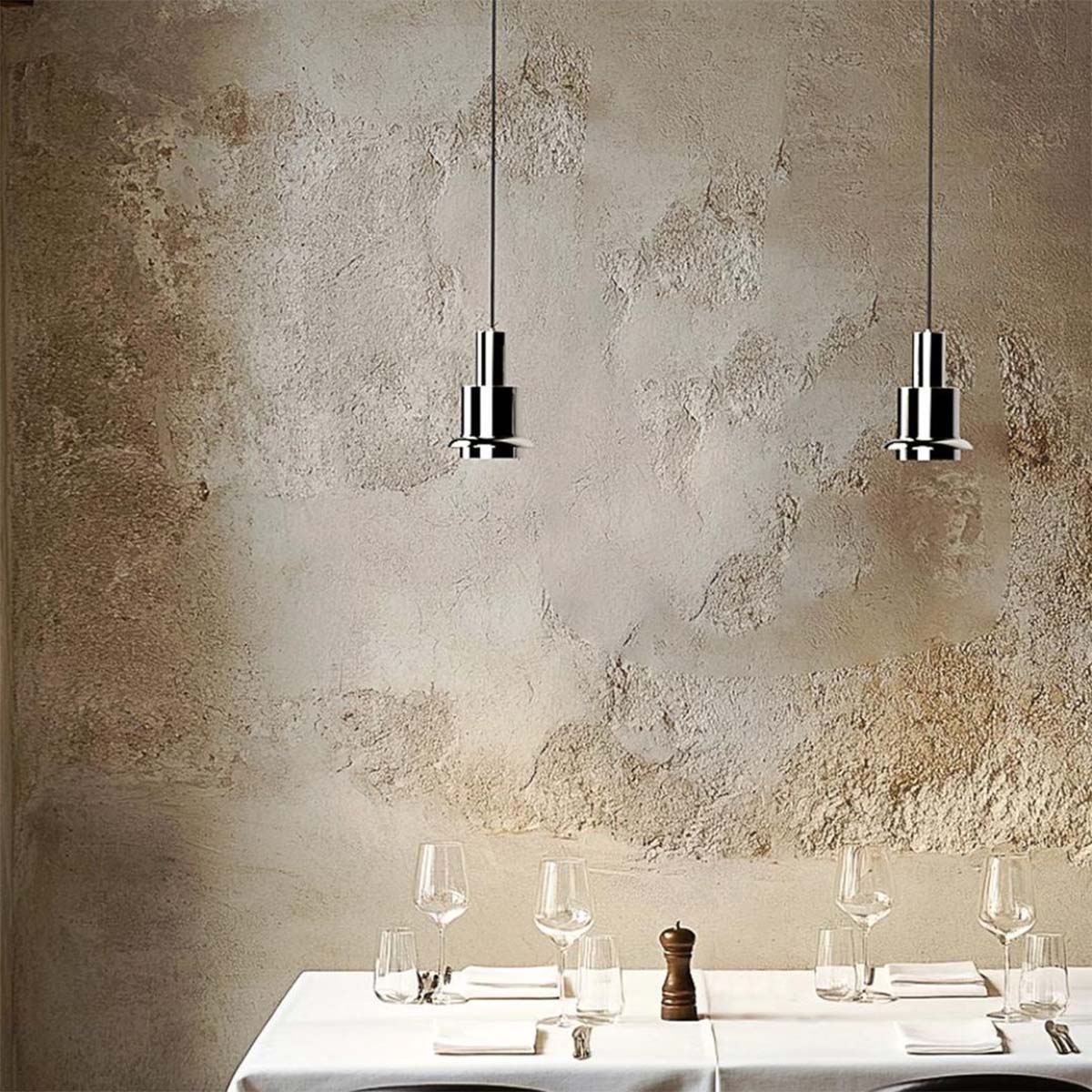 DCW Editions Chaumont 150 in Nickel über Esstisch – glänzende Nickel-Pendelleuchten setzen edle Akzente über einem fein gedeckten Tisch mit rustikaler Wandstruktur DCW Editions Chaumont 150 in Nickel über Esstisch – glänzende Nickel-Pendelleuchten setzen edle Akzente über einem fein gedeckten Tisch mit rustikaler Wandstruktur