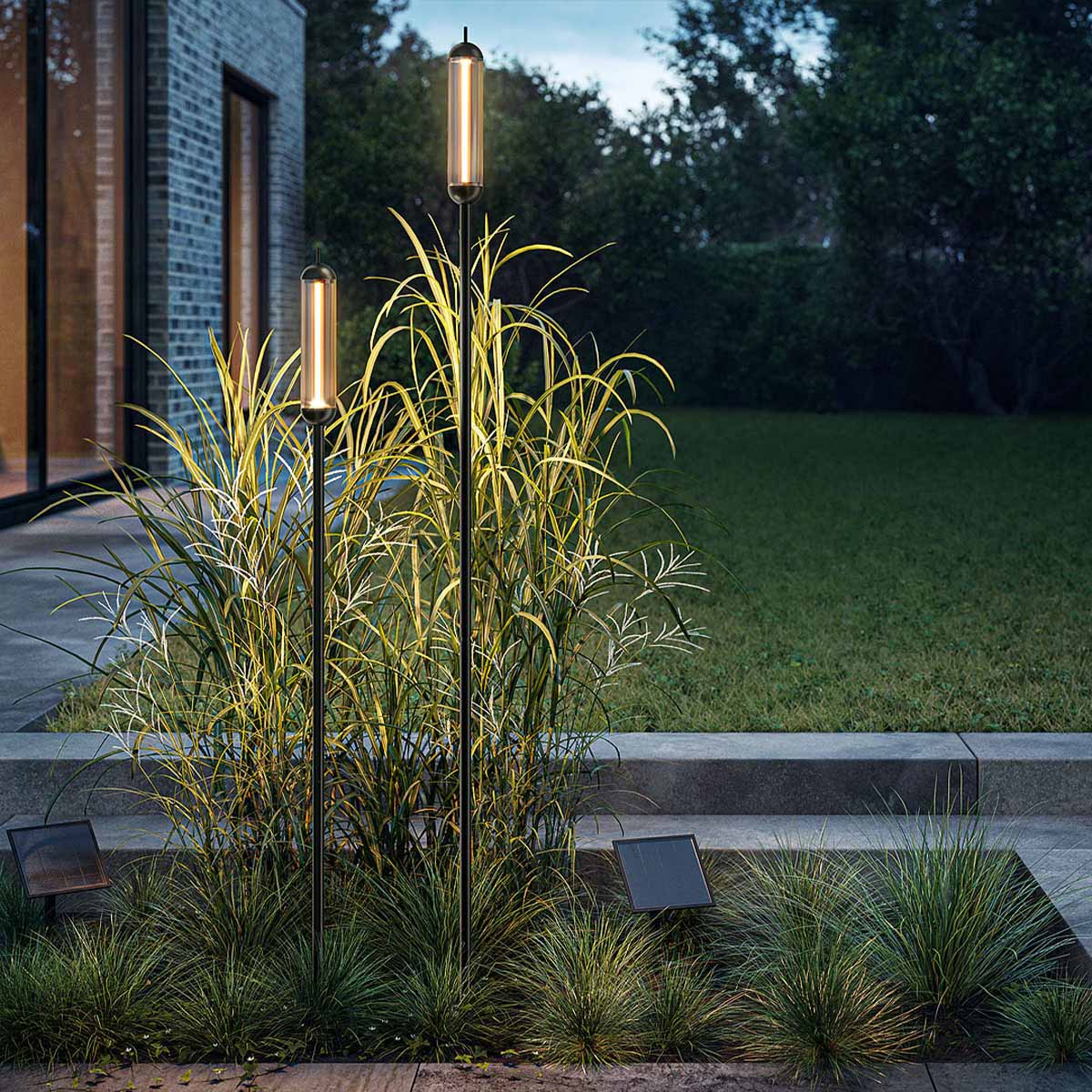 Zwei Stabförmige schwarze Erdspießleuchten mit Solarmodul und verbindungskabel im Beet im Garten