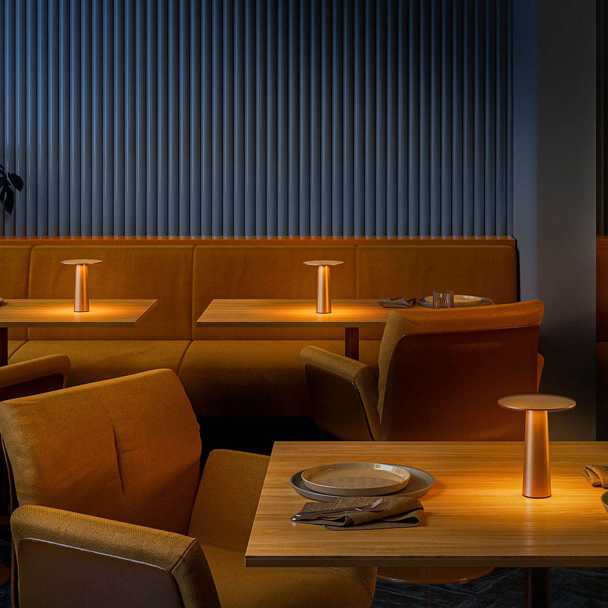 Kleine dimmbare mobile außen Akku Tischleuchte in der Farbe bronze auf den Tischen in einem Restaurant