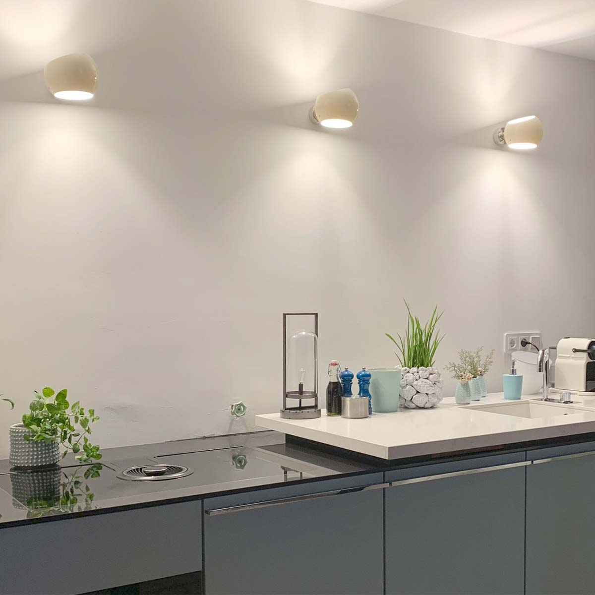 Licht im Raum White Moons 1 Drei moderne weiße Wandleuchten mit asymmetrischem Design in der Küche hängend