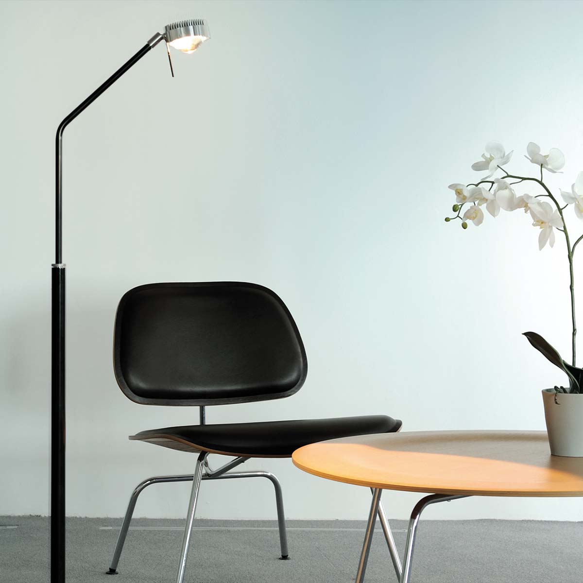 Schmale Stehleuchte neben einem Stuhl stehend