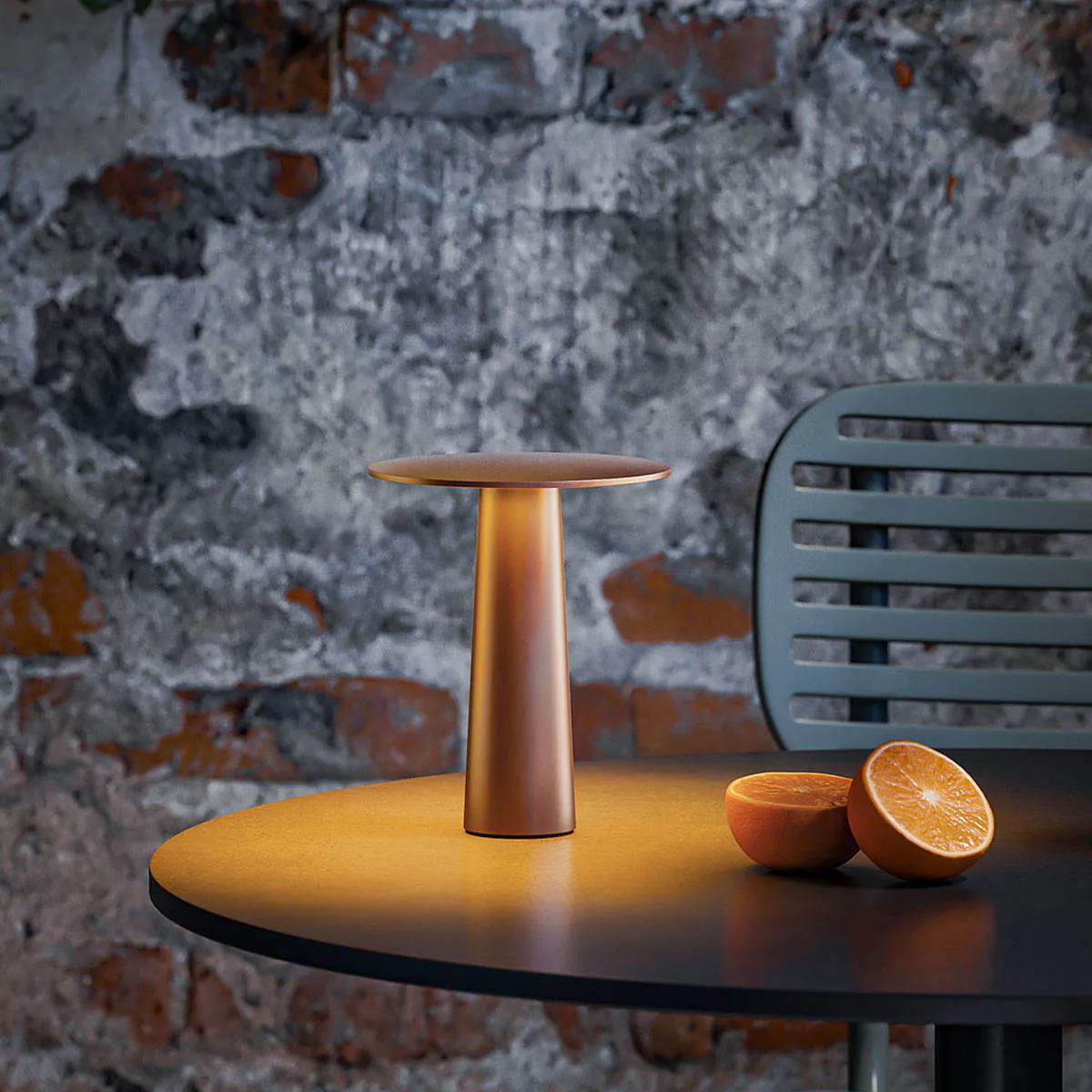 Kleine dimmbare mobile außen Akku Tischleuchte in der Farbe bronze auf einem Tisch im Garten