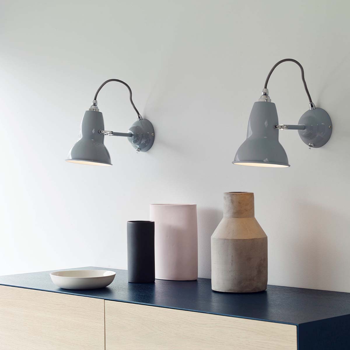 Anglepoise Original 1227 Wandleuchte, Ø: 13 cm, H: 16 cm im Wohnambiente: schwarze Design-Wandleuchte in moderner Küche mit rosafarbenen Schränken, Messingarmaturen und charakteristischem Kabelbogen.